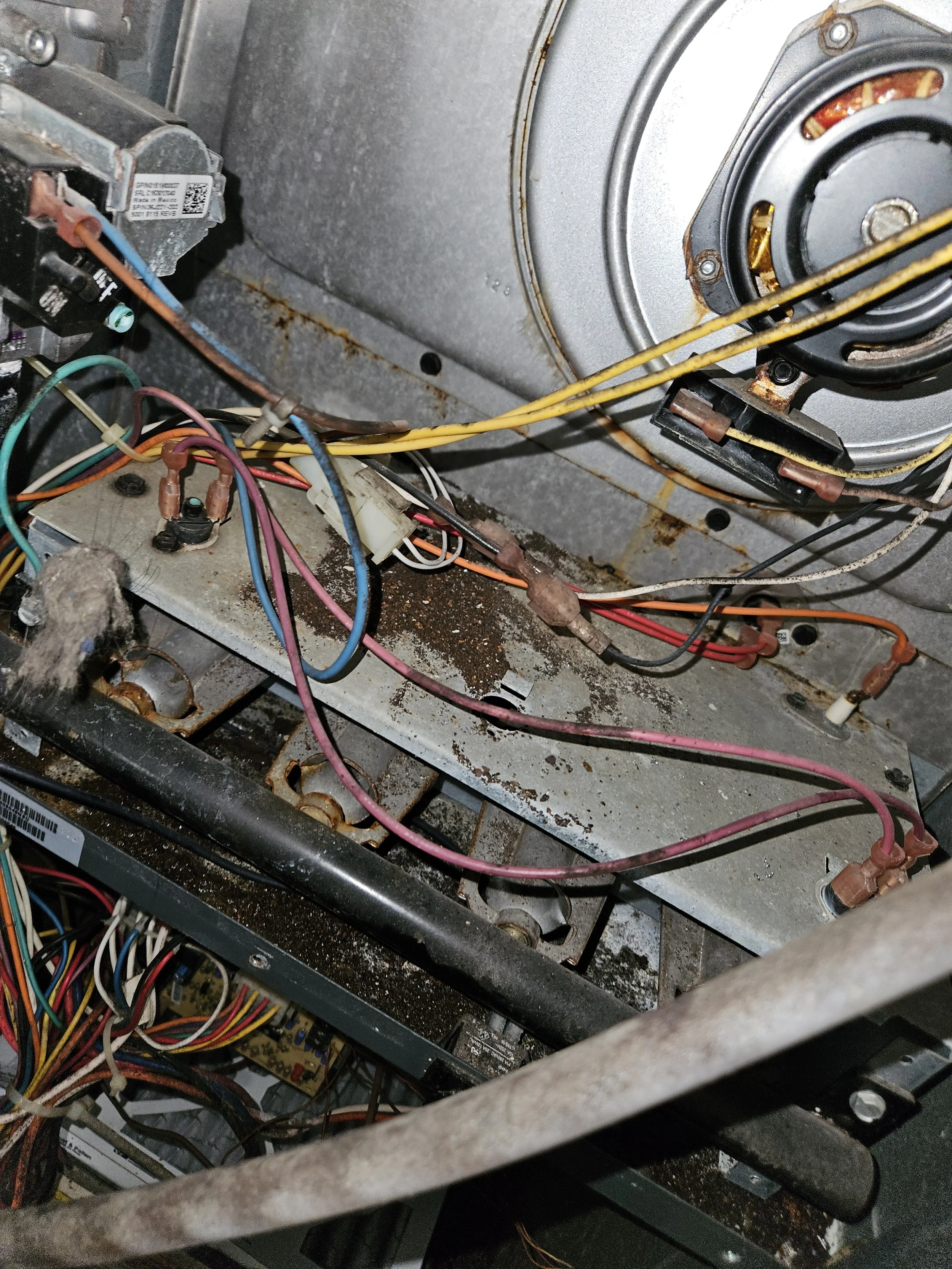 Interior view of an old, dusty, and rusted electronic or appliance machine with exposed wires, components, and rusted metal surfaces.