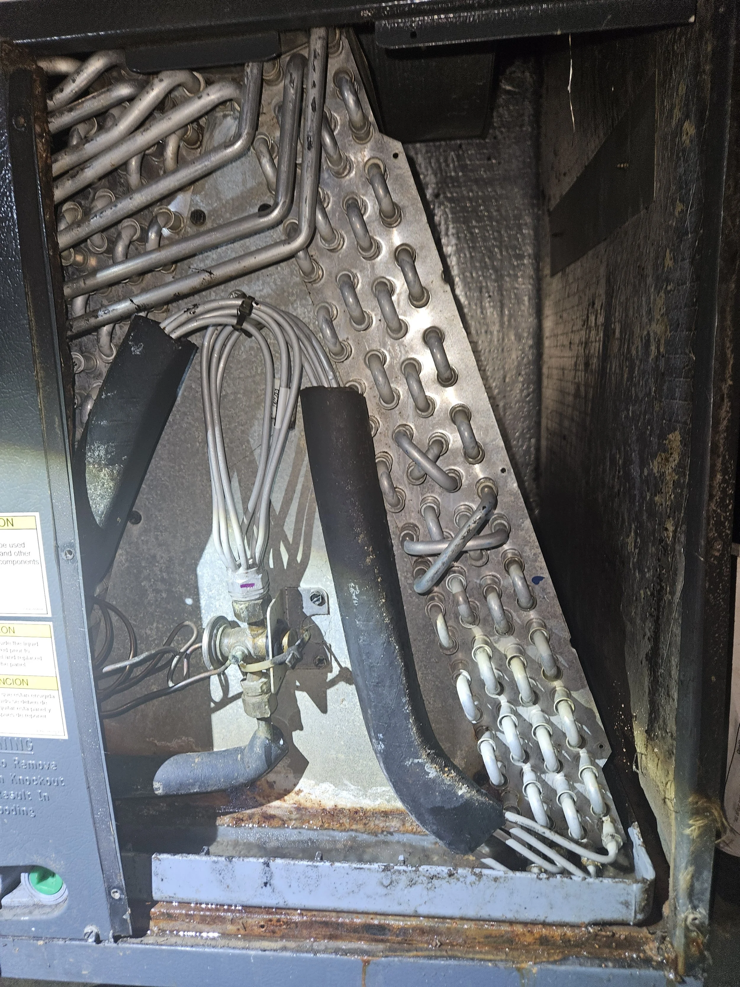 Inside an industrial or mechanical device, showing metal pipes and wires, some black foam padding, and rusted metal parts.