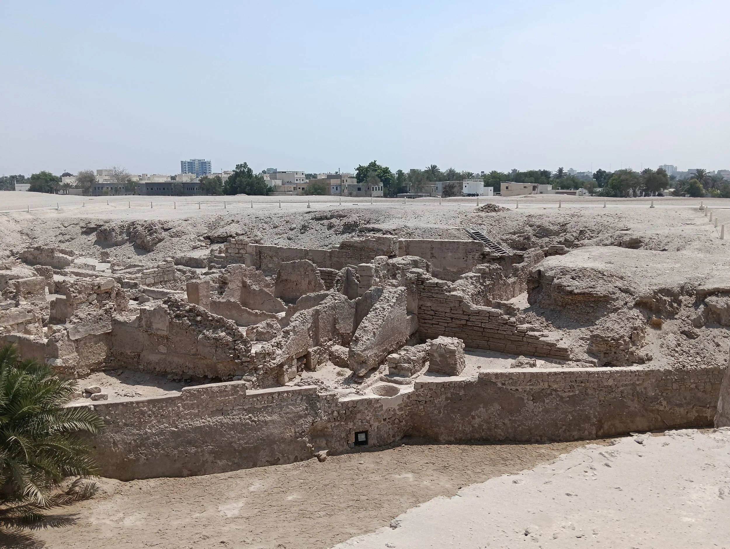Elevated view into a deep excavation with intersecting walls, small rounded stone features and openings.