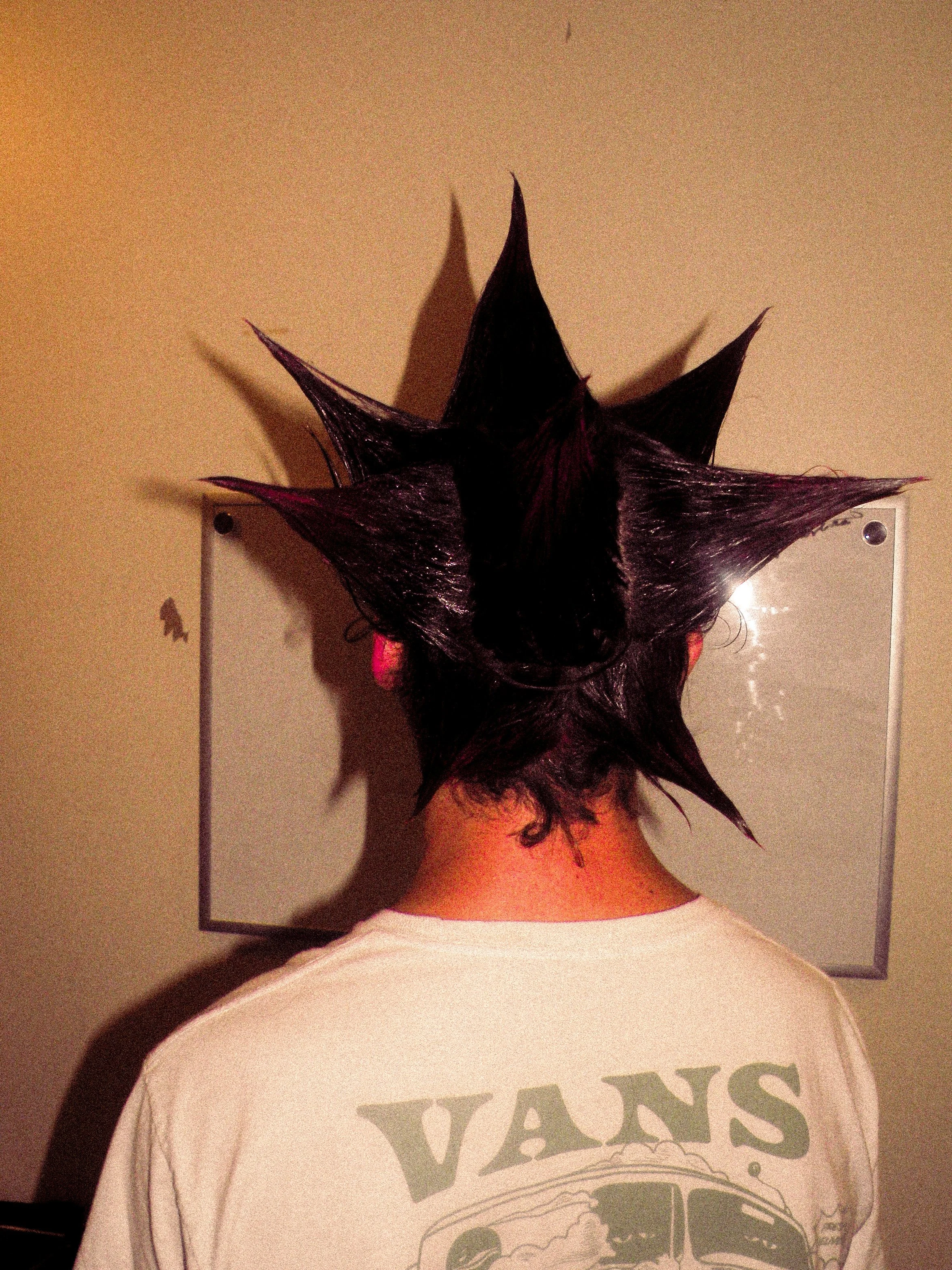 Person with spiky black and purple hair, viewed from behind, standing in front of a whiteboard.