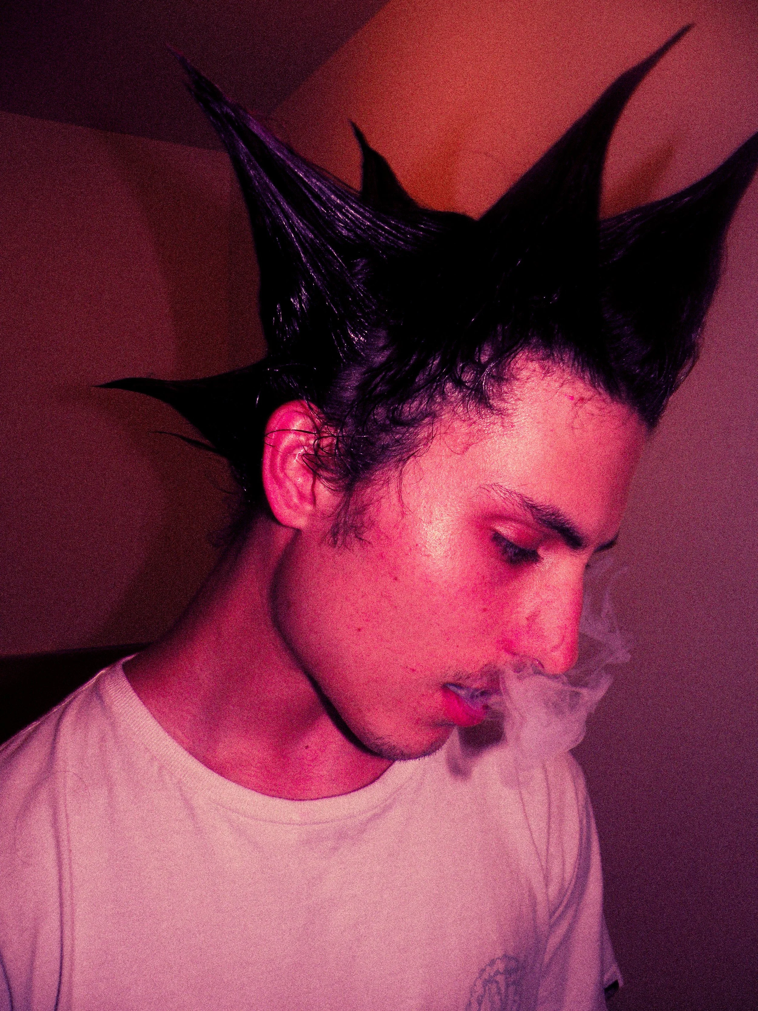 Person with spiky, wet black hair and pink skin, exhaling smoke or vapor