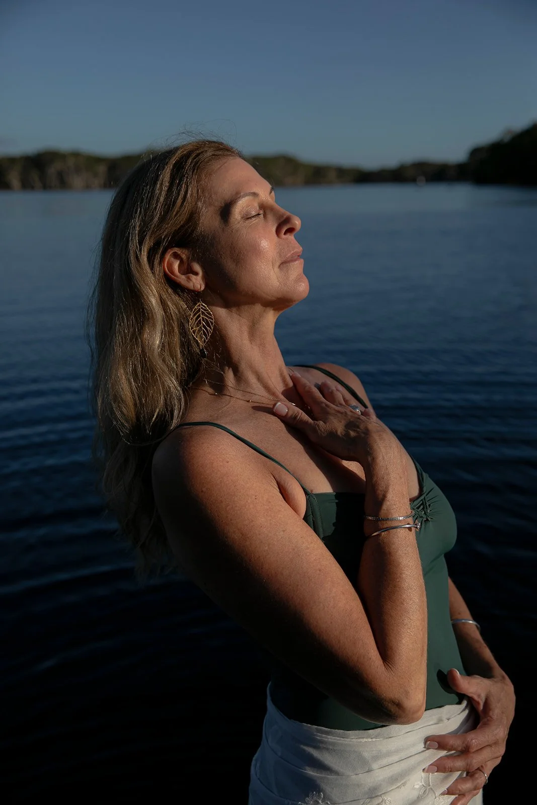 welcoming woman connecting with herself and nature in the lake