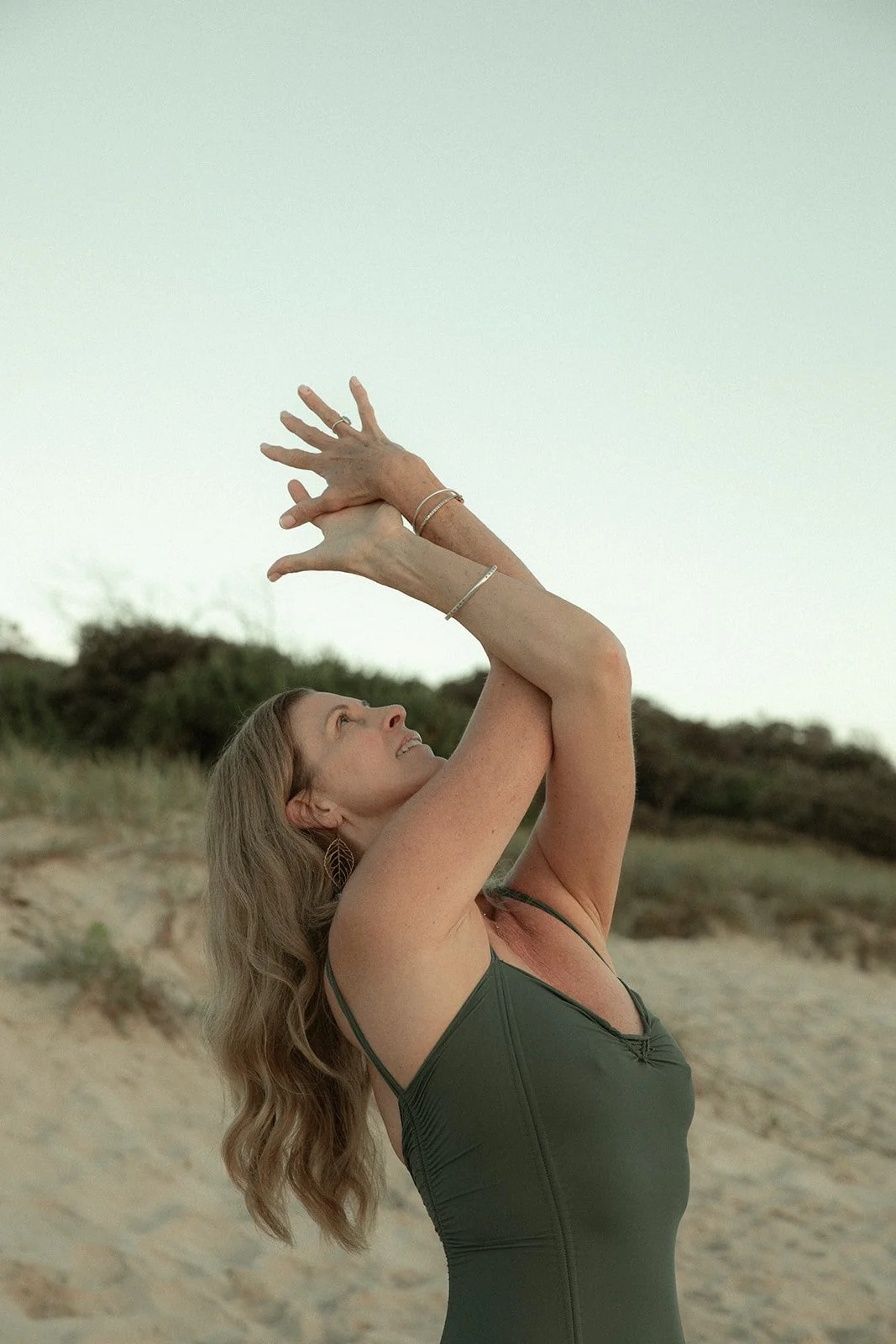 woman smiling doing a yoga pose during sunset