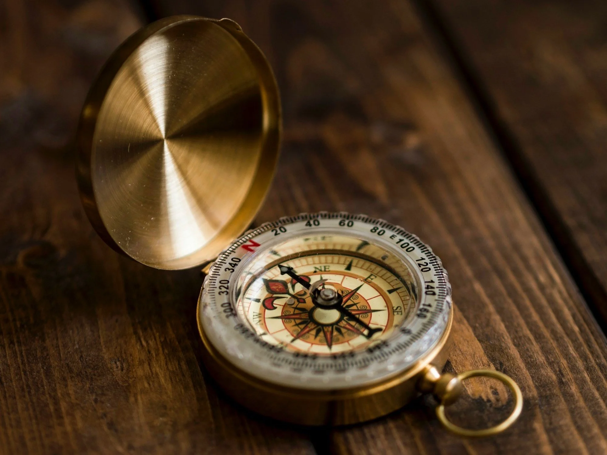 Antike Kompass auf Holztisch mit offenem Deckel.