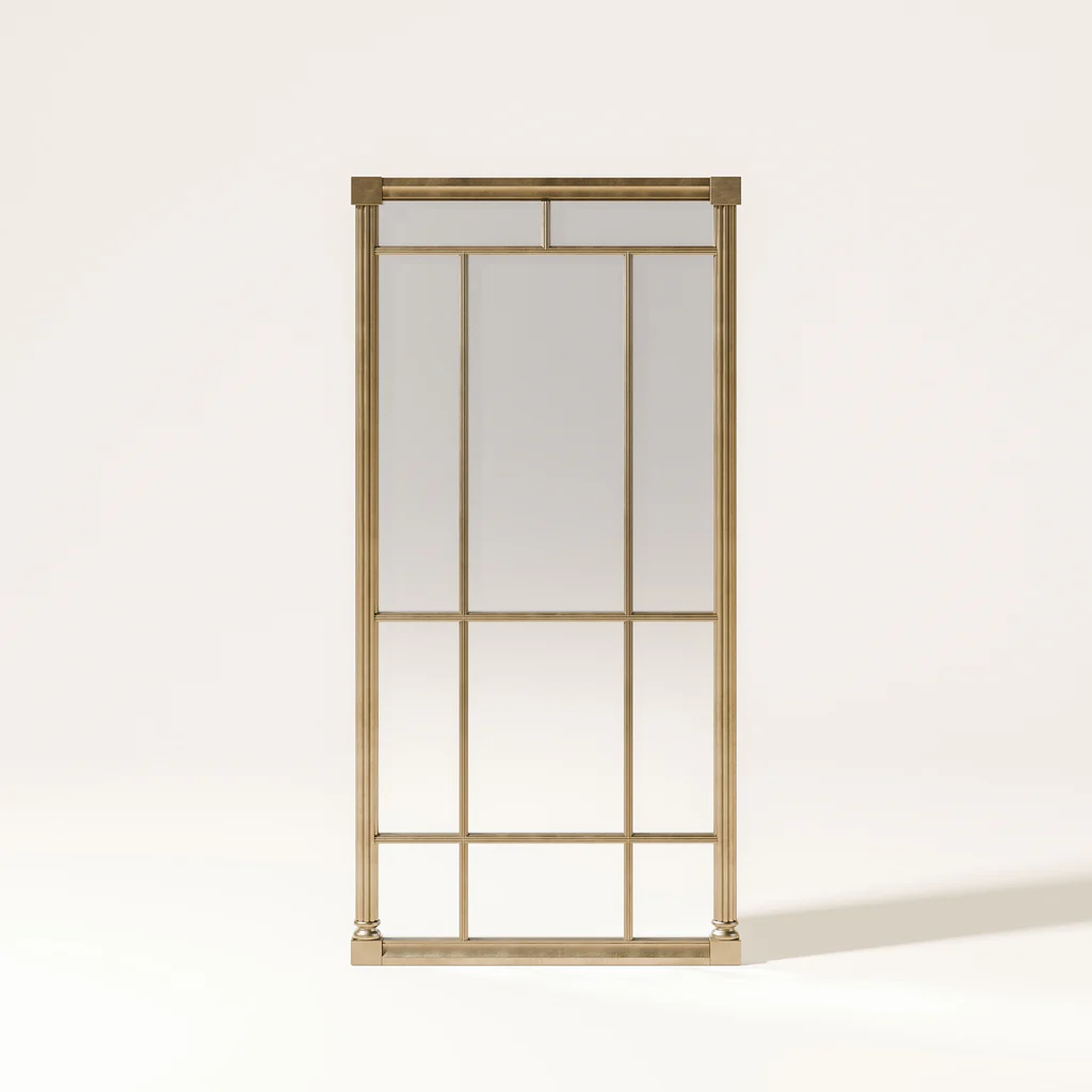 A tall, gold-colored, metal mirror with multiple rectangular panes, standing against a plain, cream-colored wall.