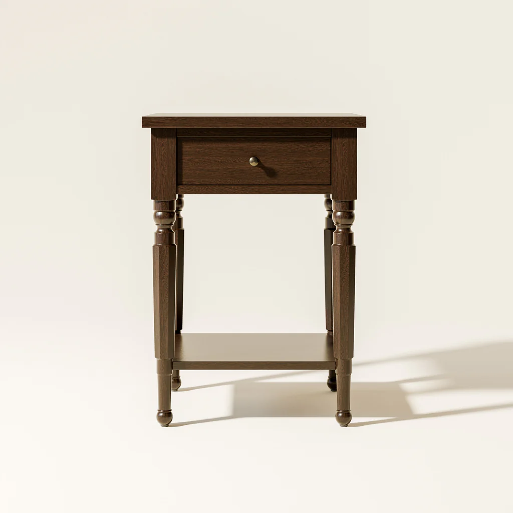 A wooden side table with a drawer and lower shelf, standing against a plain light background.