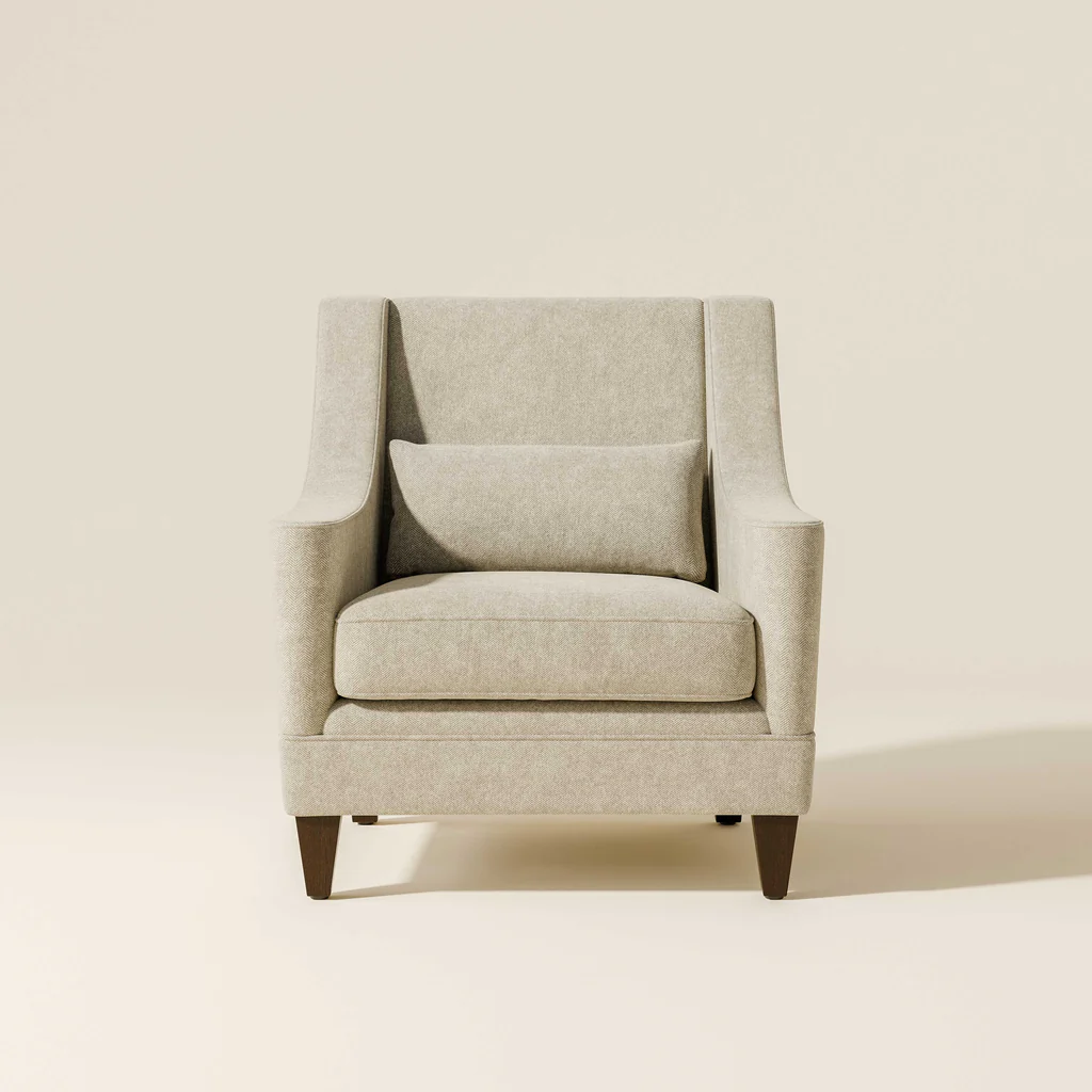 A beige upholstered armchair with a matching pillow against a plain, light-colored background.