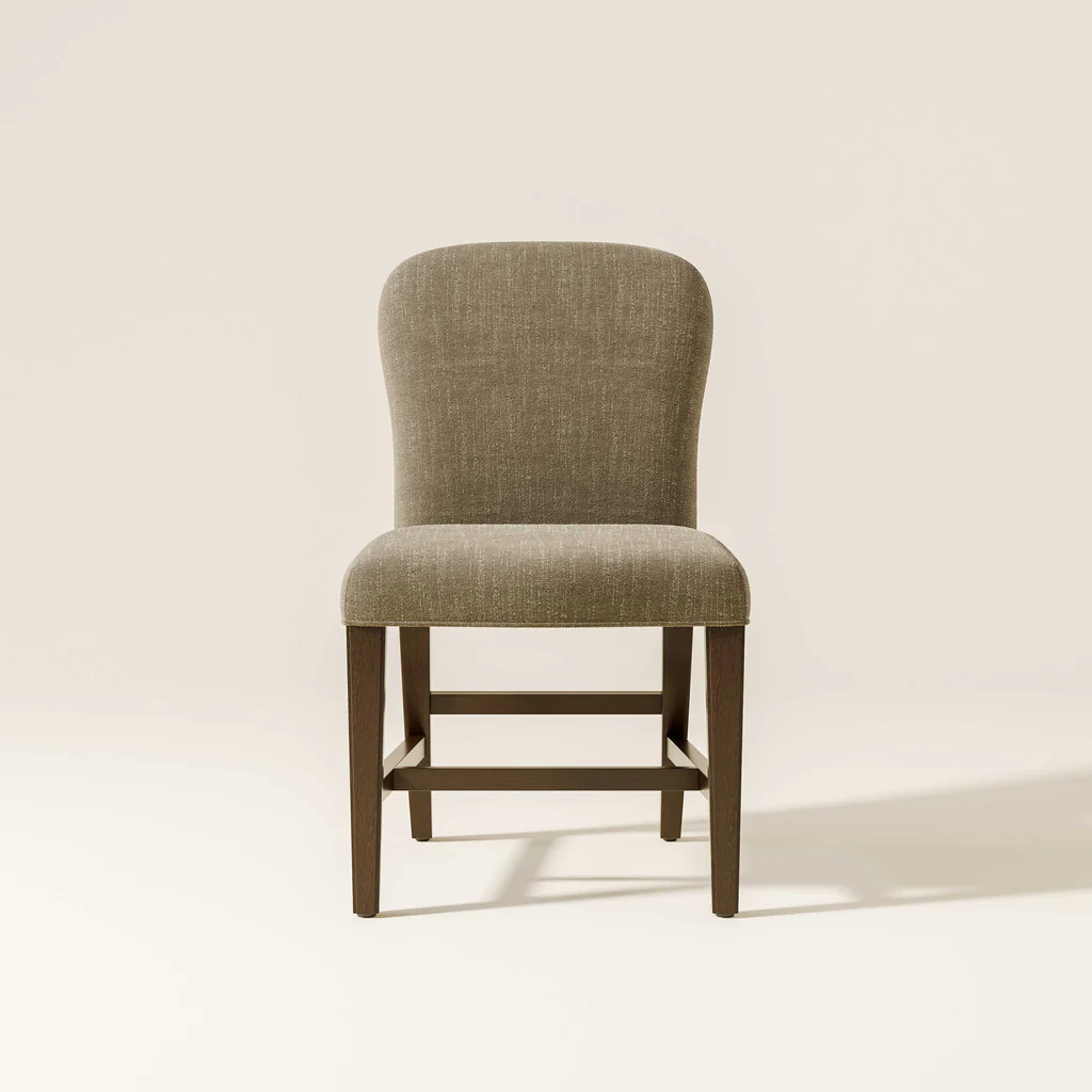 A beige upholstered dining chair with wooden legs against a light background.