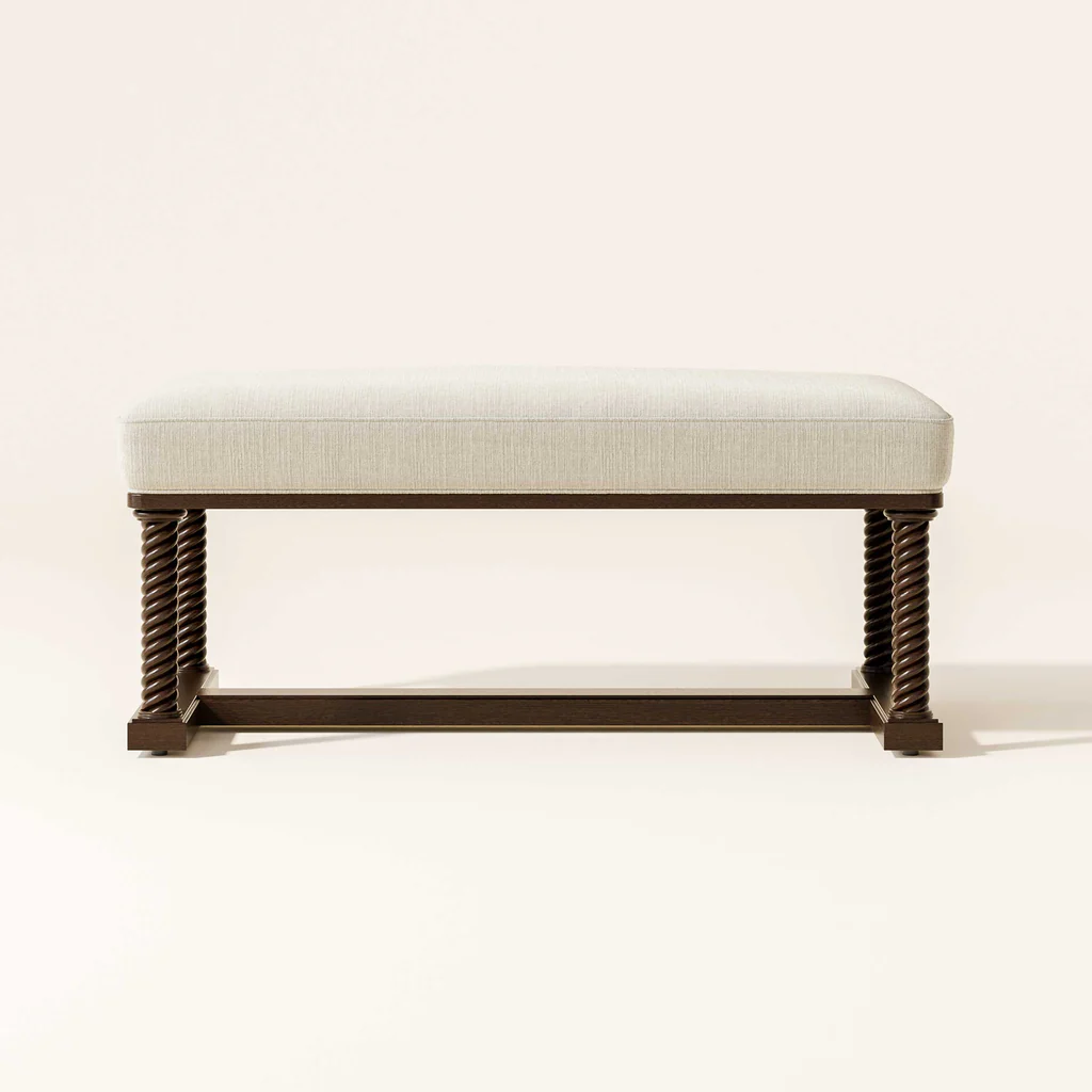 A beige upholstered bench with dark brown twisted wood legs against a plain, off-white background.