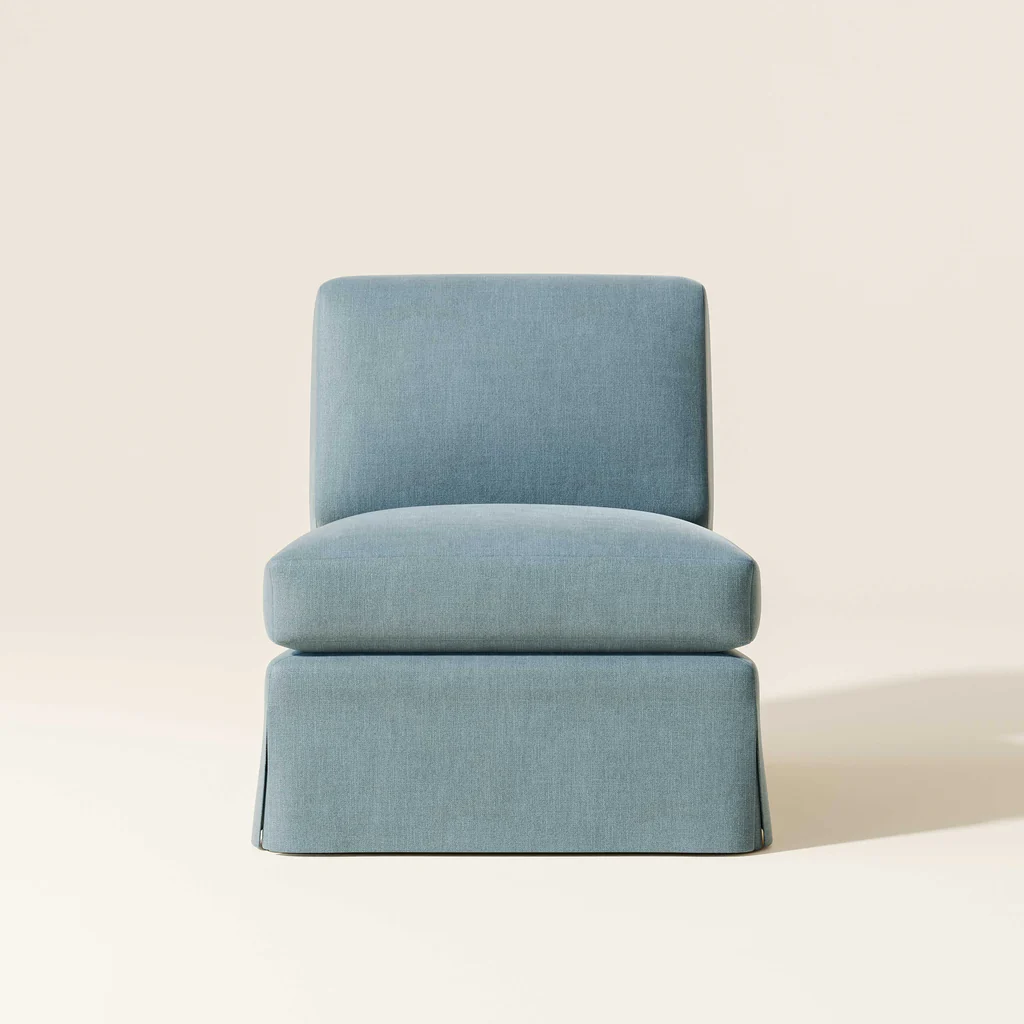 A light blue upholstered chair with a skirted base against a plain, neutral background.