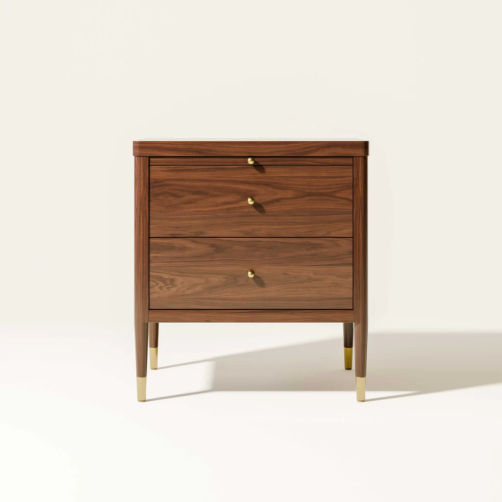 A wooden three-drawer dresser with gold knobs and gold tips on four tapered legs against a plain white background.