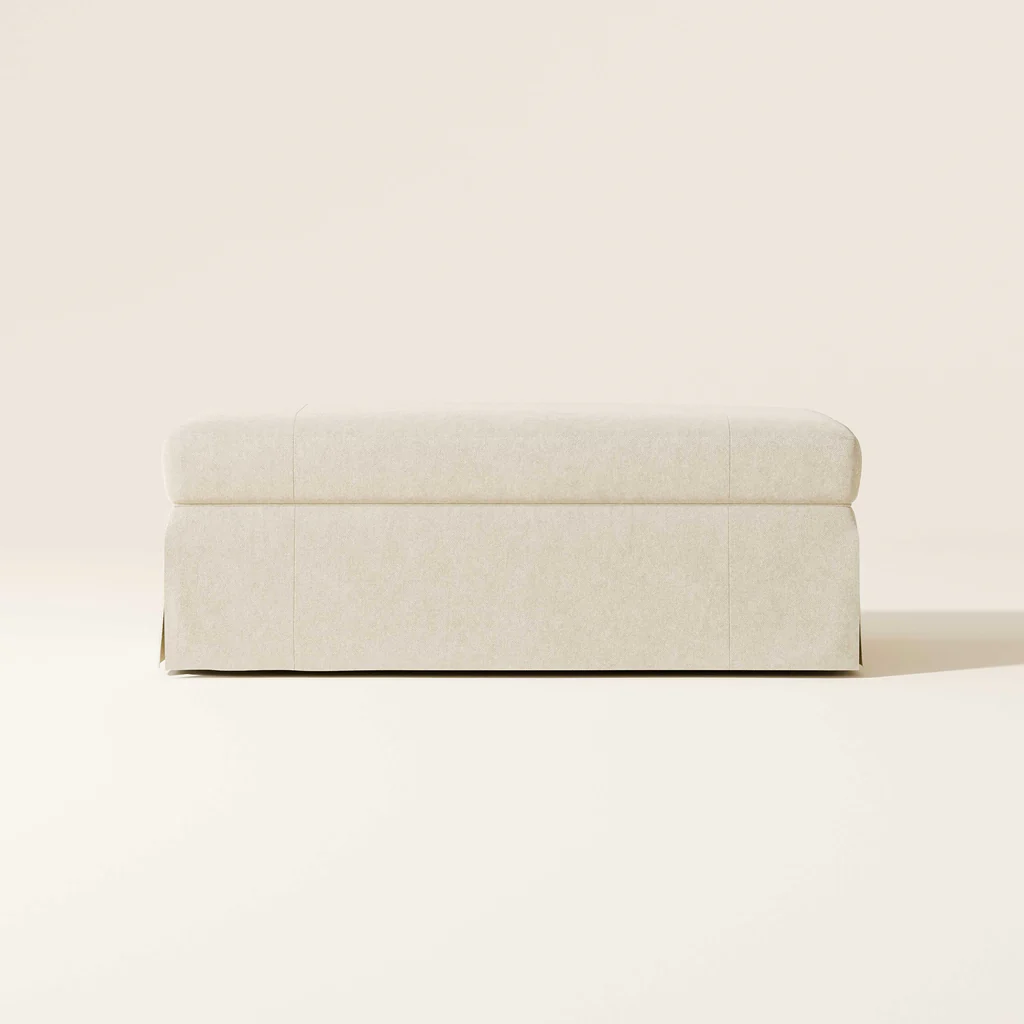 A beige upholstered bench against a plain beige background.