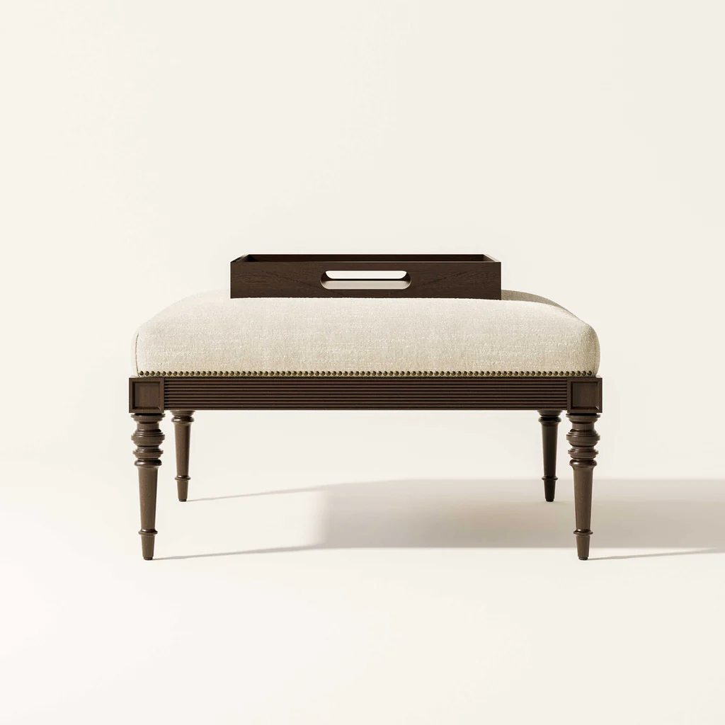 A beige upholstered bench with turned wooden legs and a dark wooden tray on top, set against a plain white background.