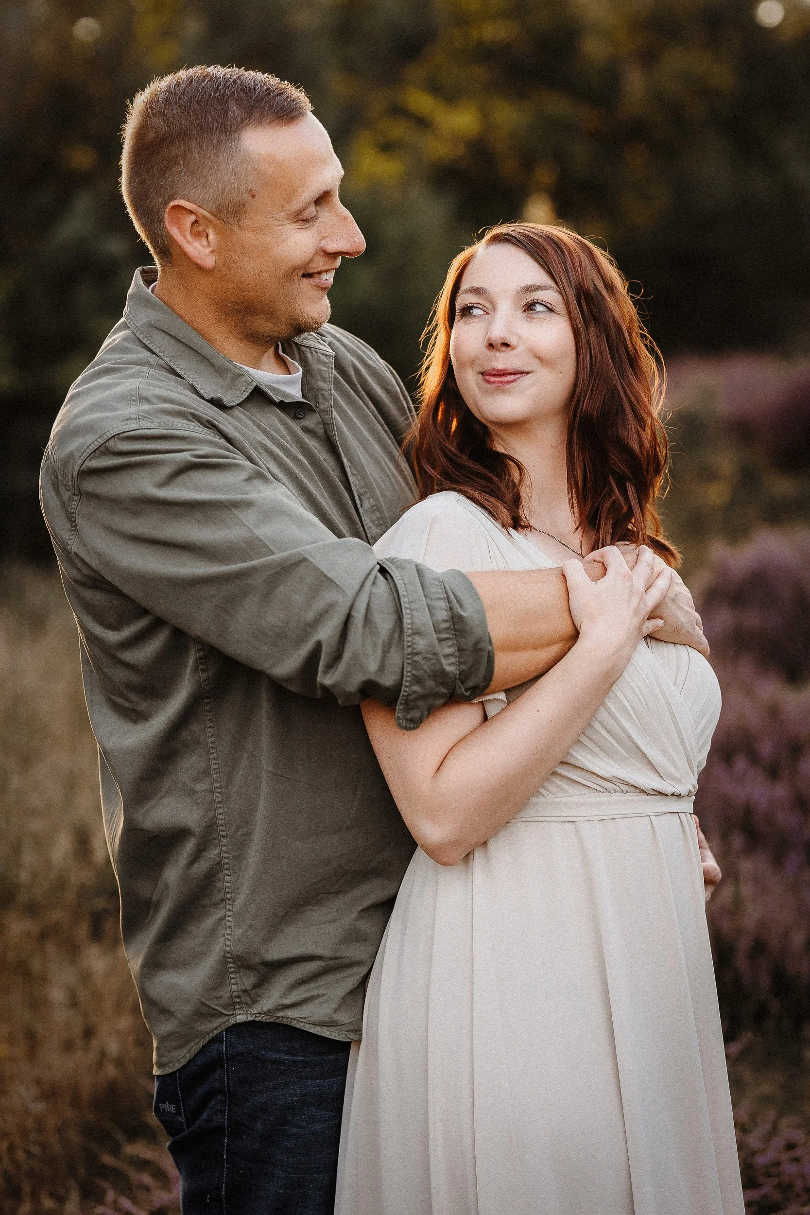 Paar steht auf einer Wiese und schmunzeln sich an