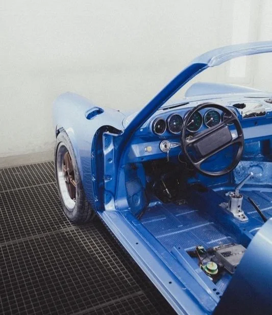 Intérieur d'une voiture bleue, sans sièges, volant et tableau de bord visibles.