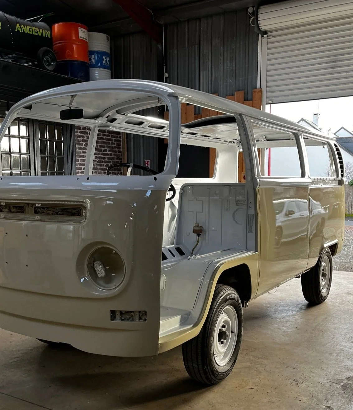 Une carrosserie de véhicule en cours de restauration dans un atelier, sans les pièces intérieures et les phares, avec un toit en partie installé