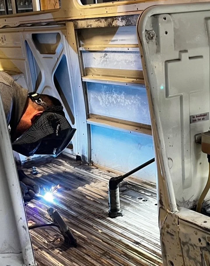 Une personne en protection de soudure effectuant une soudure dans l'intérieur d'un van Volkswagen