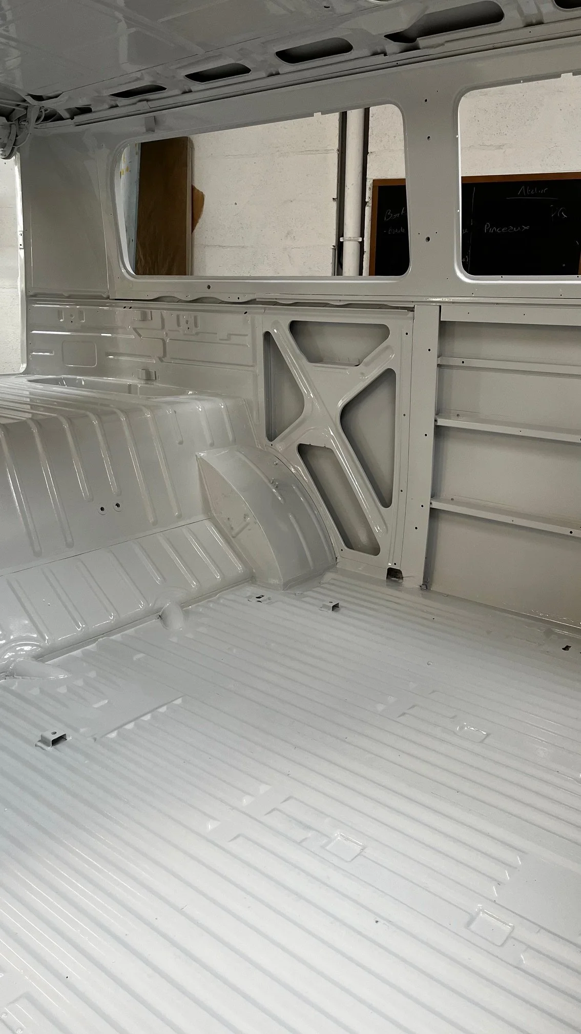 Intérieur vide d'un combi Volkswagen, avec une structure métallique blanche propre et lisse.