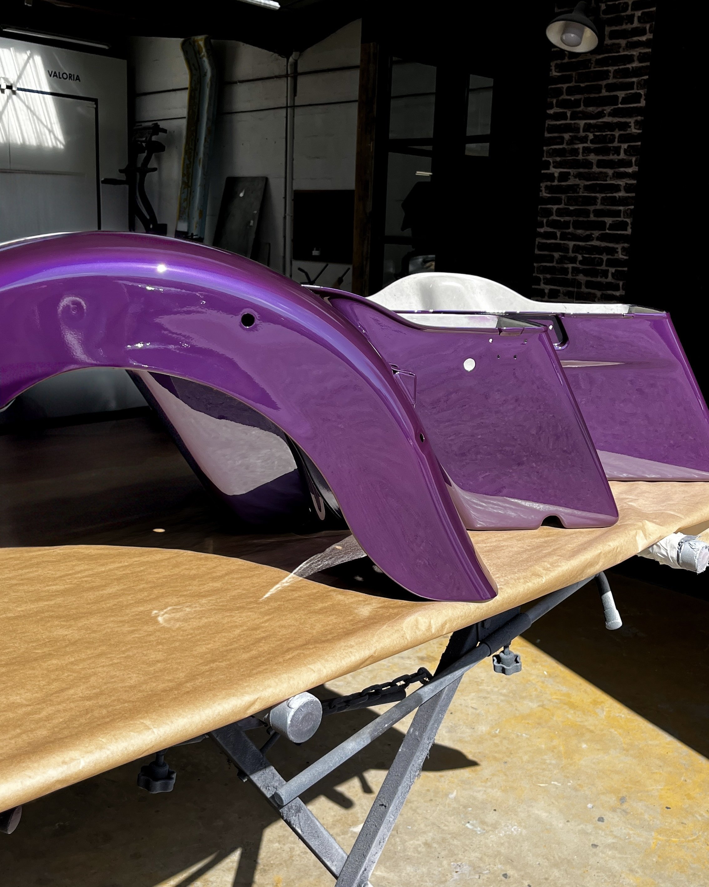 Pièces de carrosserie violettes sur une table dans un atelier.