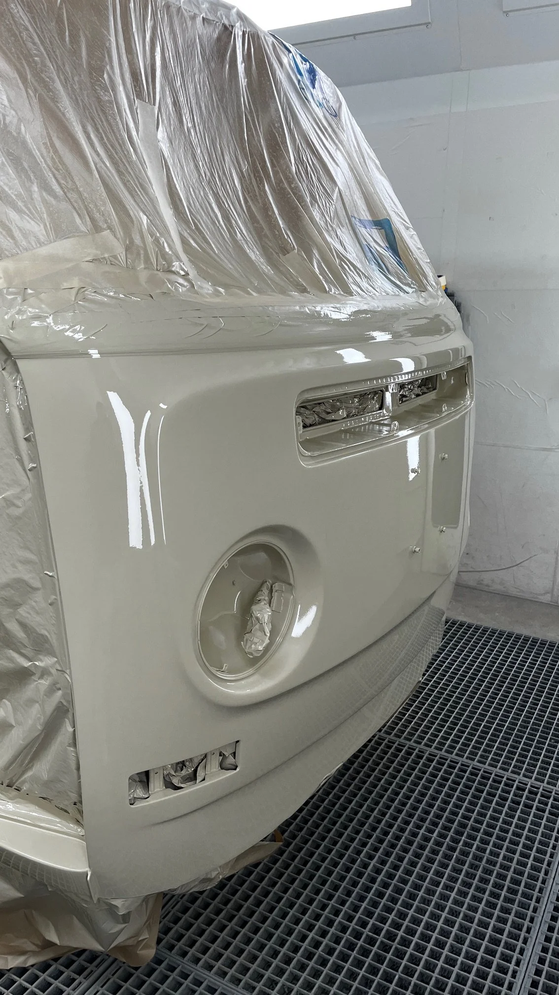 Un combi Volkswagen en cours de peinture, beige, dans une cabine de peinture automobile