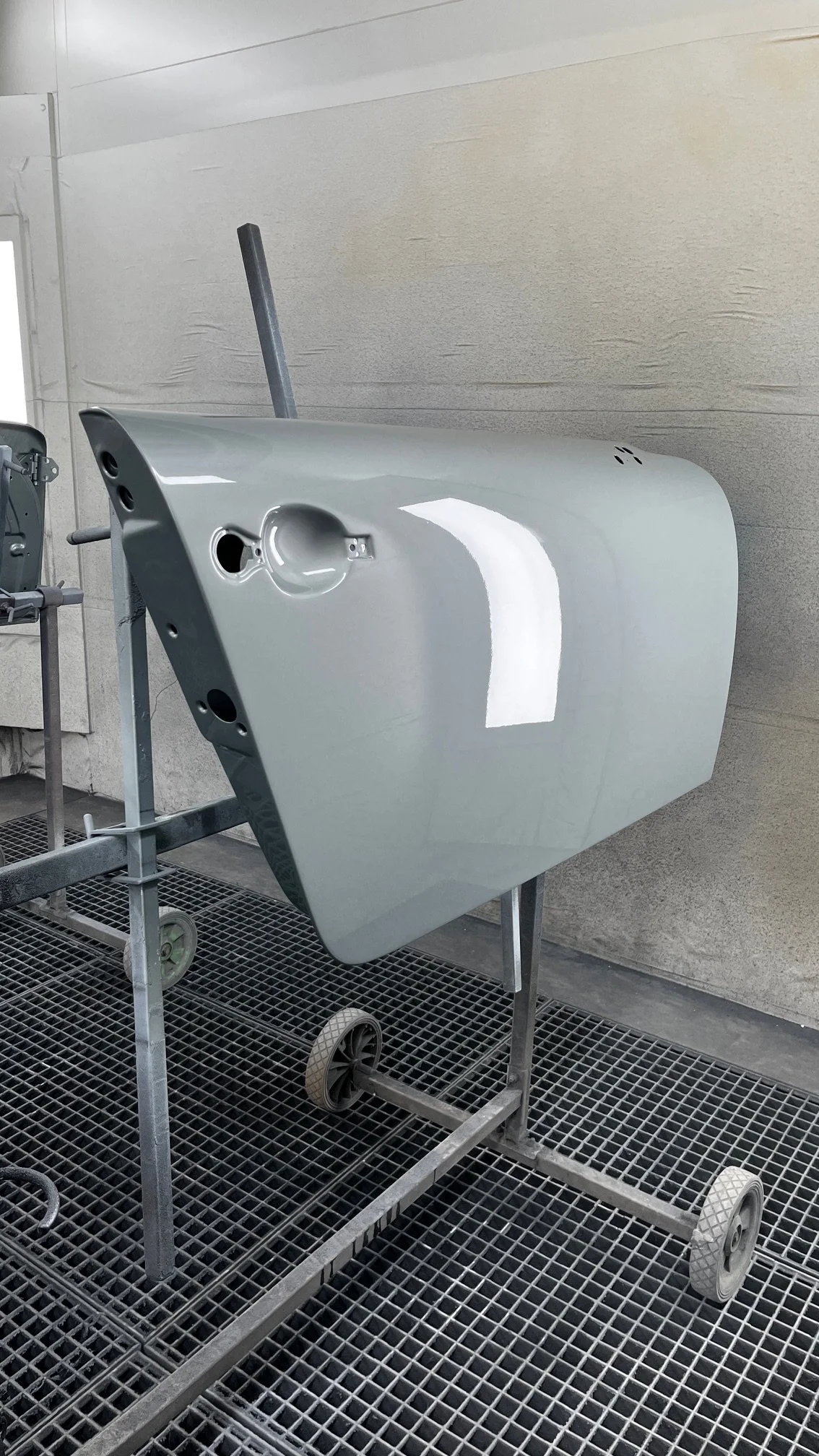 porte automobile peinte en gris brillant, suspendue sur un support dans une cabine