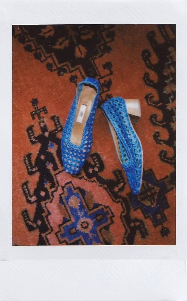 Pair of blue open-toe high-heeled shoes on a patterned rug.