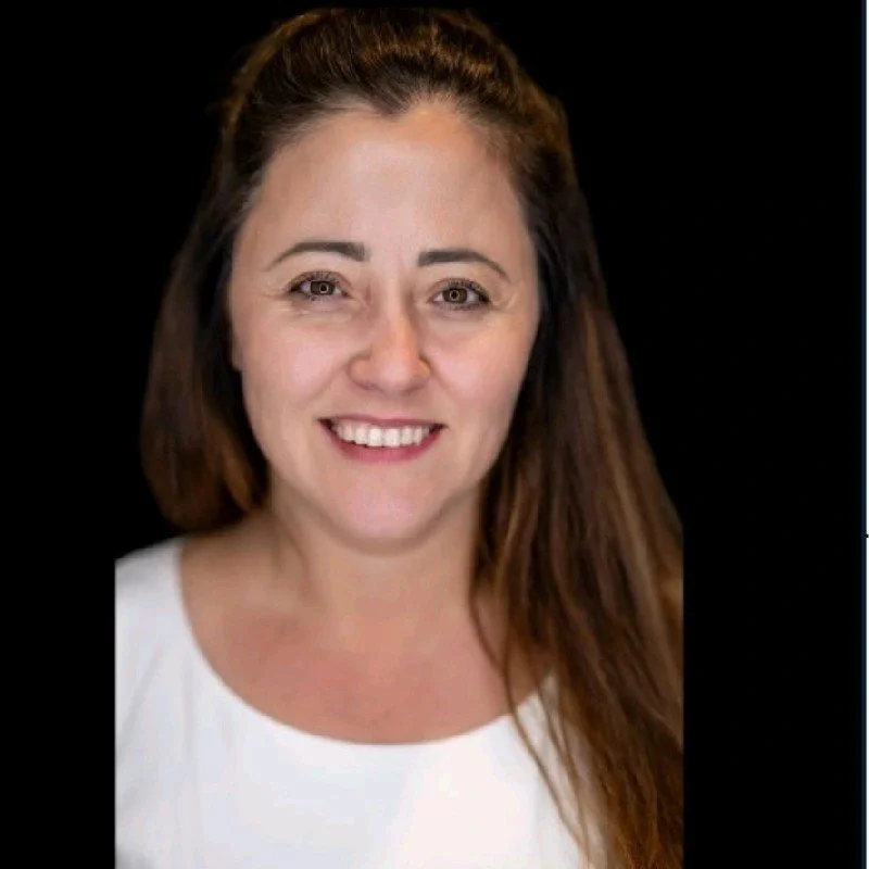 Smiling woman with long hair and a white shirt against a black background.