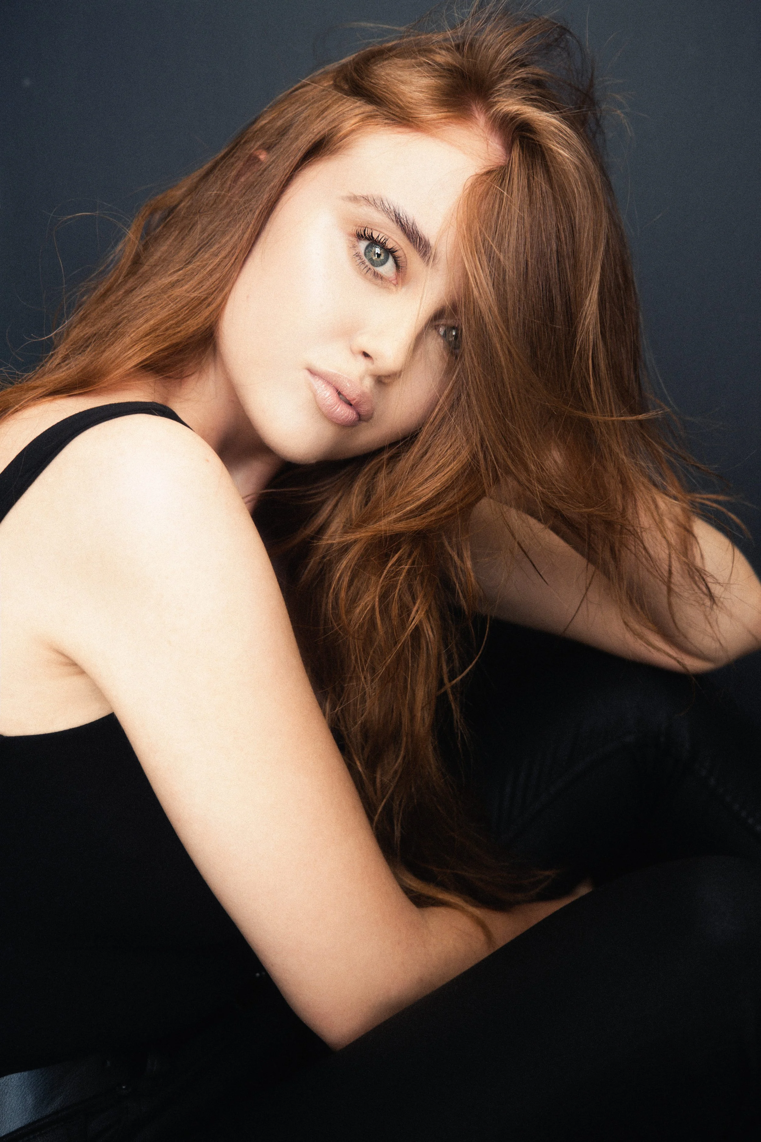 Portrait of DANIELLE Laubscher from AURA Models with long, wavy red hair, wearing a black top, looking at the camera with a neutral expression.