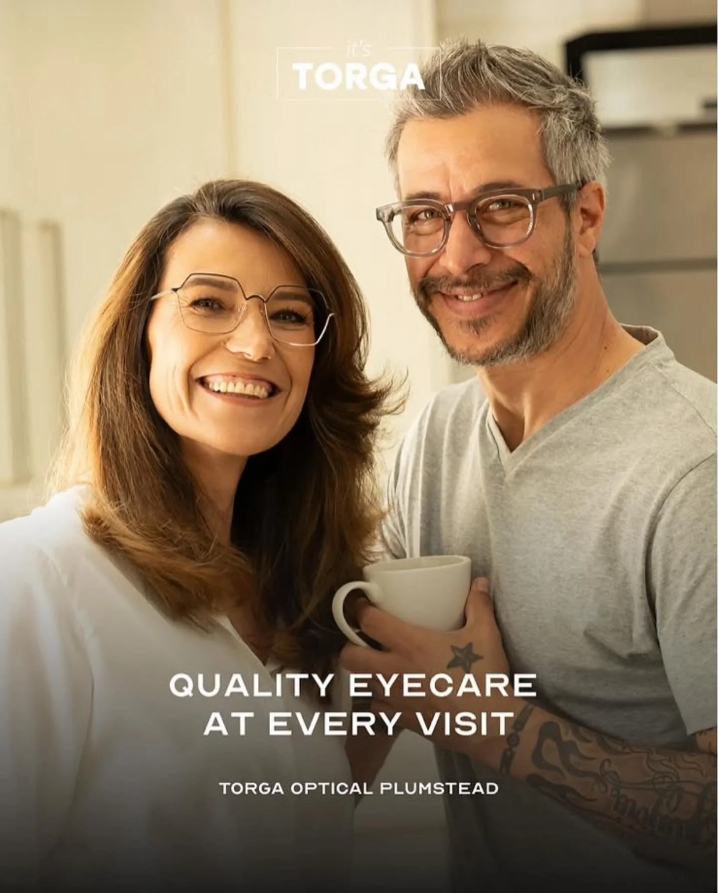 DESIRE Campbell and FEDERICO Fernandez from AURA Models smiling indoors, both wearing eyeglasses, with the woman holding a white mug. Text on the image reads, 'it's T ORGA,' 'QUALITY EYECARE AT EVERY VISIT,' and 'TORGA OPTICAL PLUMSTEAD.'