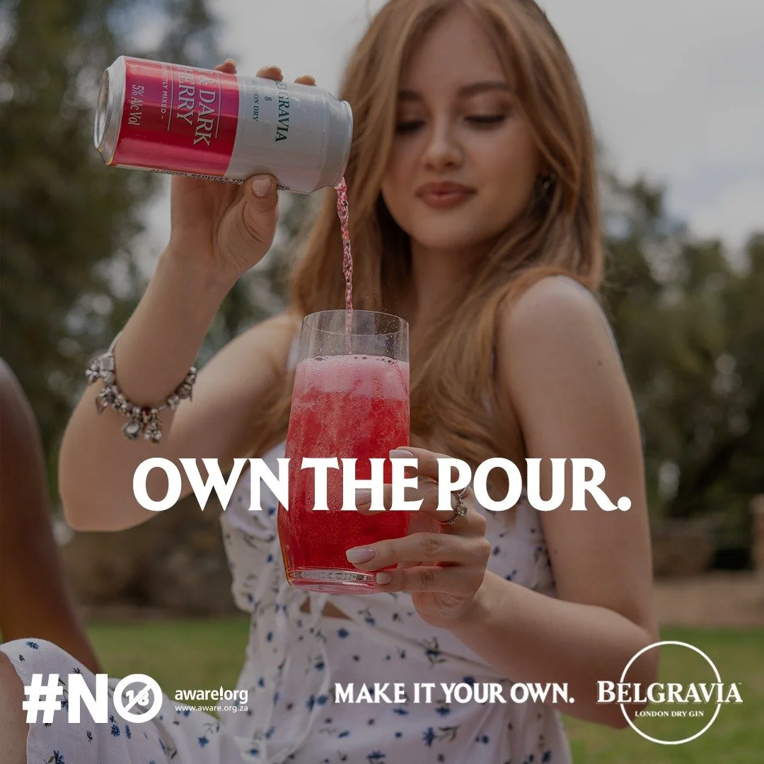 DANIELLE Laubscher from AURA Models pouring a pink drink from a can into a glass outdoors with trees in the background. The text on the image says 'OWN THE POUR. MAKE IT YOUR OWN.' and includes the logos for Aware and Belgravia London Dry Gin.