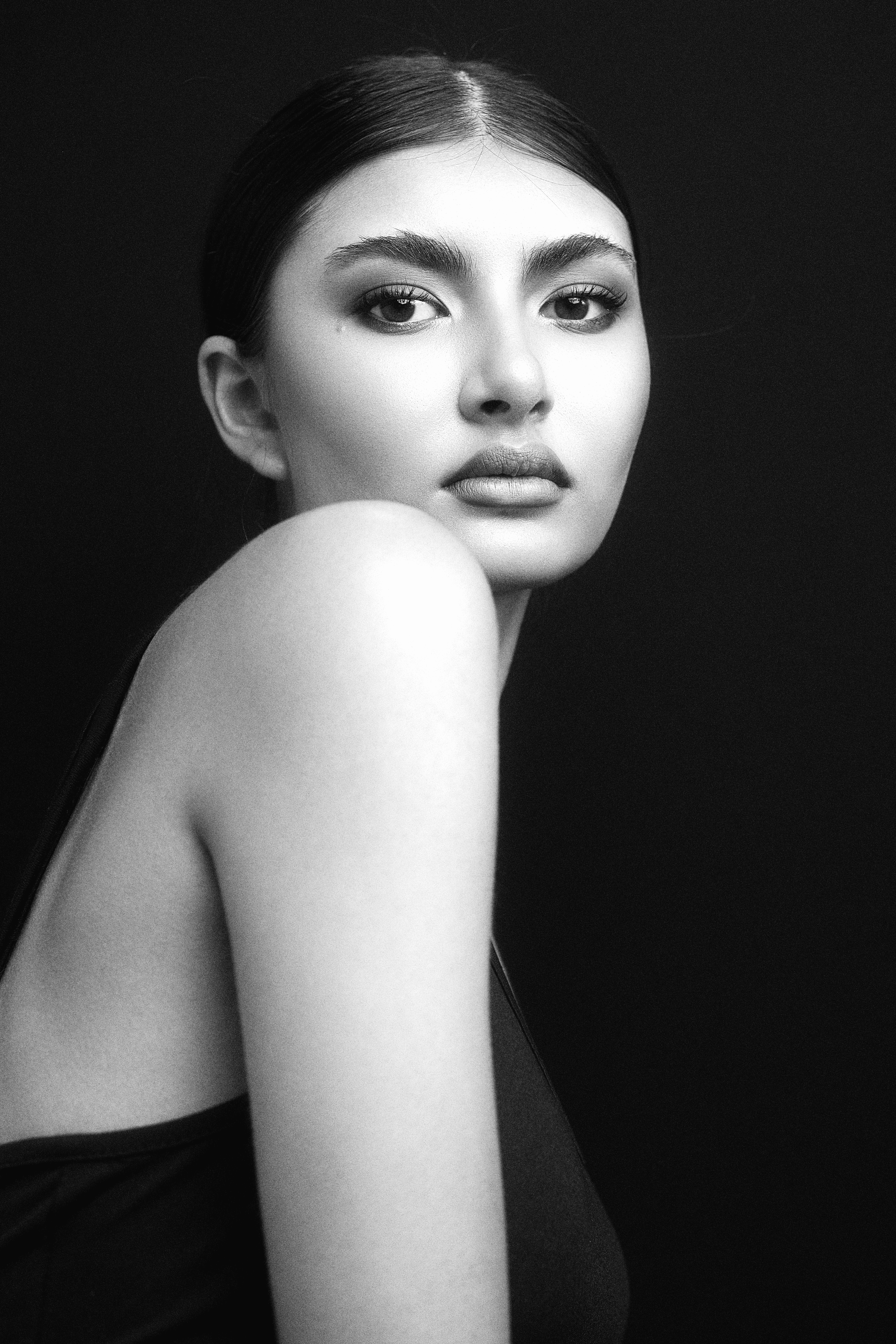 Black and white close-up photograph of KEIRA Louw from AURA Models with dark hair, wearing a sleeveless top, looking directly at the camera with a serious expression.