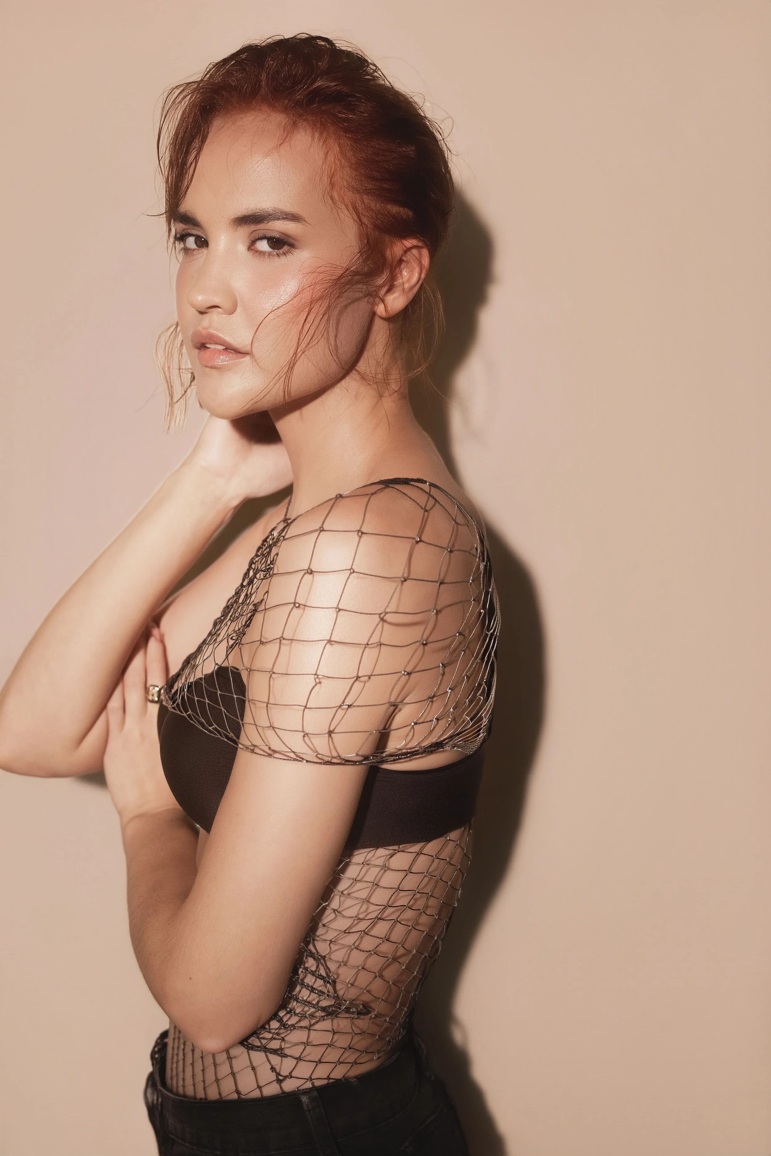 MARINET Potgieter from AURA Models Urban with brown hair styled in a loose updo, wearing a black strapless top and a sheer, fishnet-like accessory with small embellishments. 