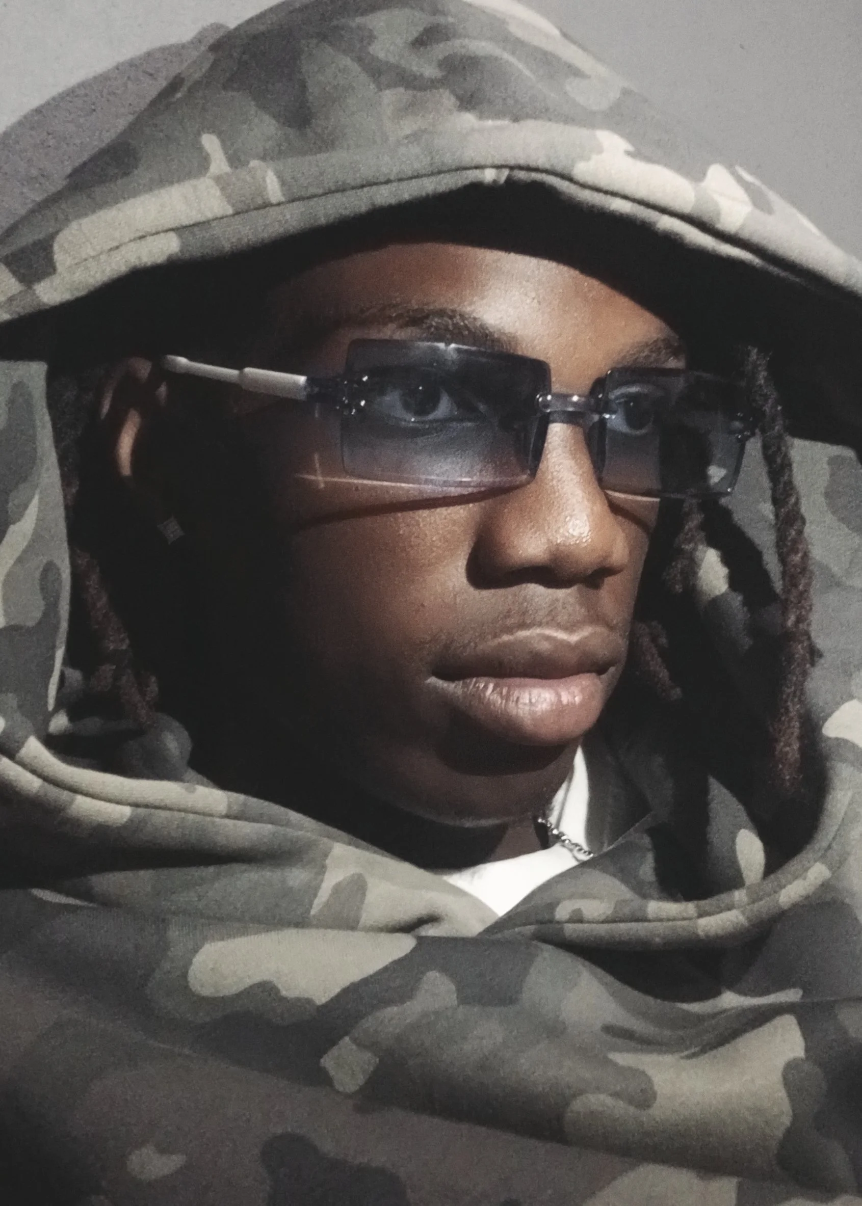 TSHEDZA Ramavheya from AURA Models wearing a camouflage hoodie, sunglasses, and with dreadlocks.