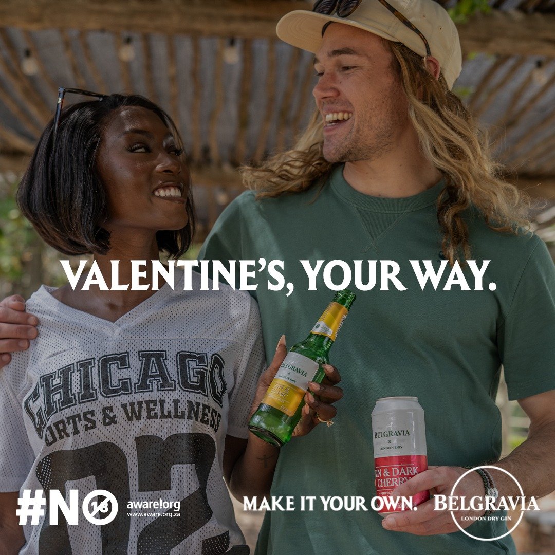 ONA COnstantin and NEIL Marais from AURA Models holding drinks, one in a Chicago sports jersey and the other in a green shirt and cap, under a wooden canopy, celebrating Valentine's Day.