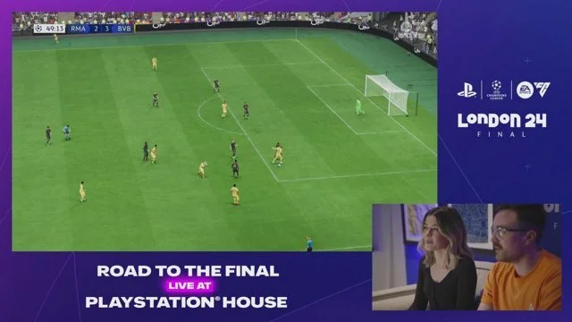 A soccer match between Real Madrid and Borussia Dortmund in progress, with players on the field, score 2-3, in the 49th minute, displayed on a screen. The event is part of the London 24 Final, live at PlayStation House, with two commentators watching and discussing.