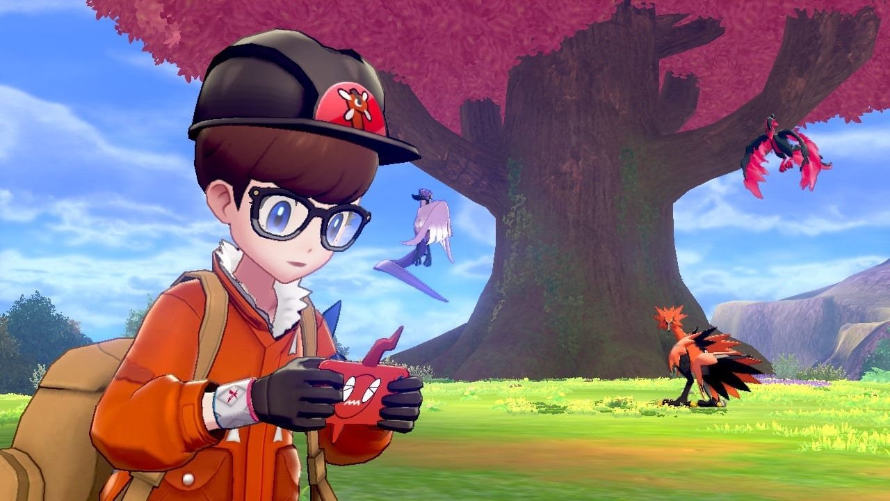 A young male character with glasses and a black cap with a Pokémon design, wearing an orange jacket and carrying a backpack, stands outside holding a small red device. Behind him is a large tree with pink leaves, and several Pokémon are visible nearby, including a purple and white dragon-like Pokémon flying near the tree, and two bird Pokémon on the ground, one orange and black, and another flying at the top of the tree.
