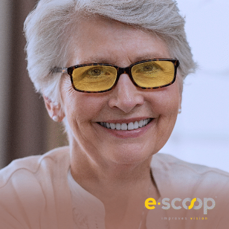 A smiling older woman with short gray hair wearing black glasses with yellow-tinted lenses.