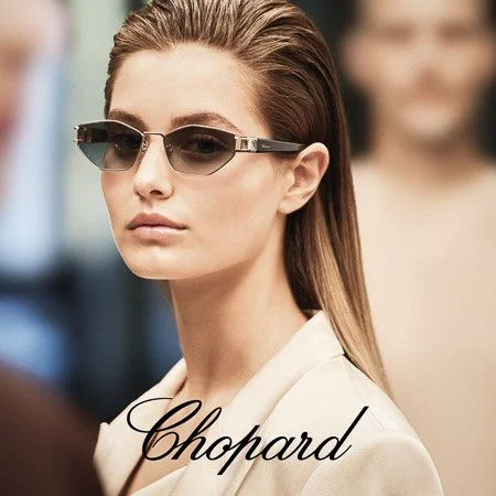 A young woman wearing designer sunglasses model Happy Diamonds made by Chopard. The word "Chopard" written in cursive