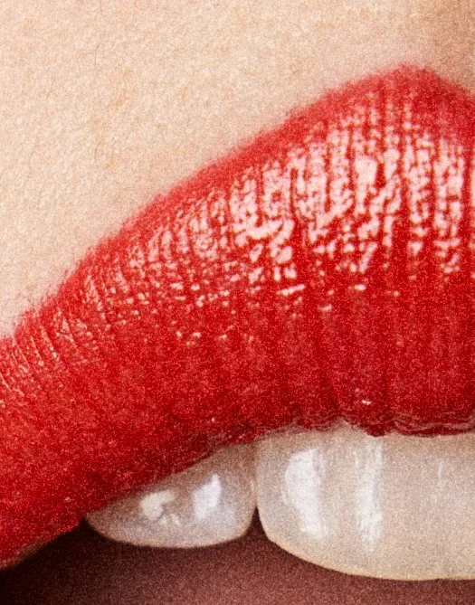 Close-up of red lipstick on lips and teeth showing.