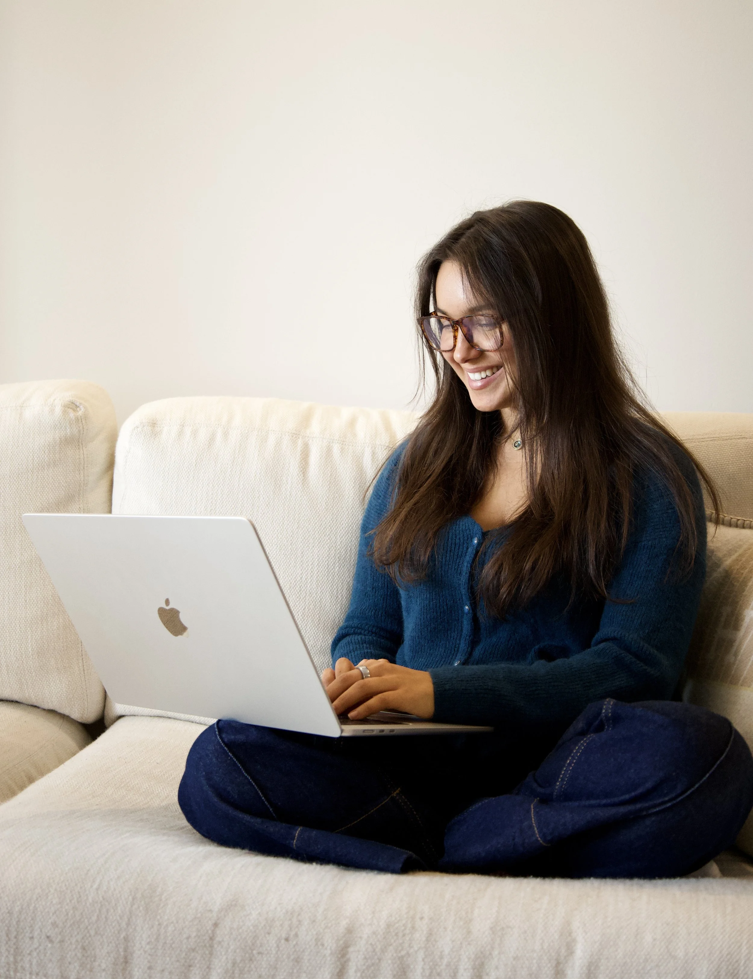 Dr. Sonya Arrigo, naturopathic doctor, smiling on a sofa with her laptop