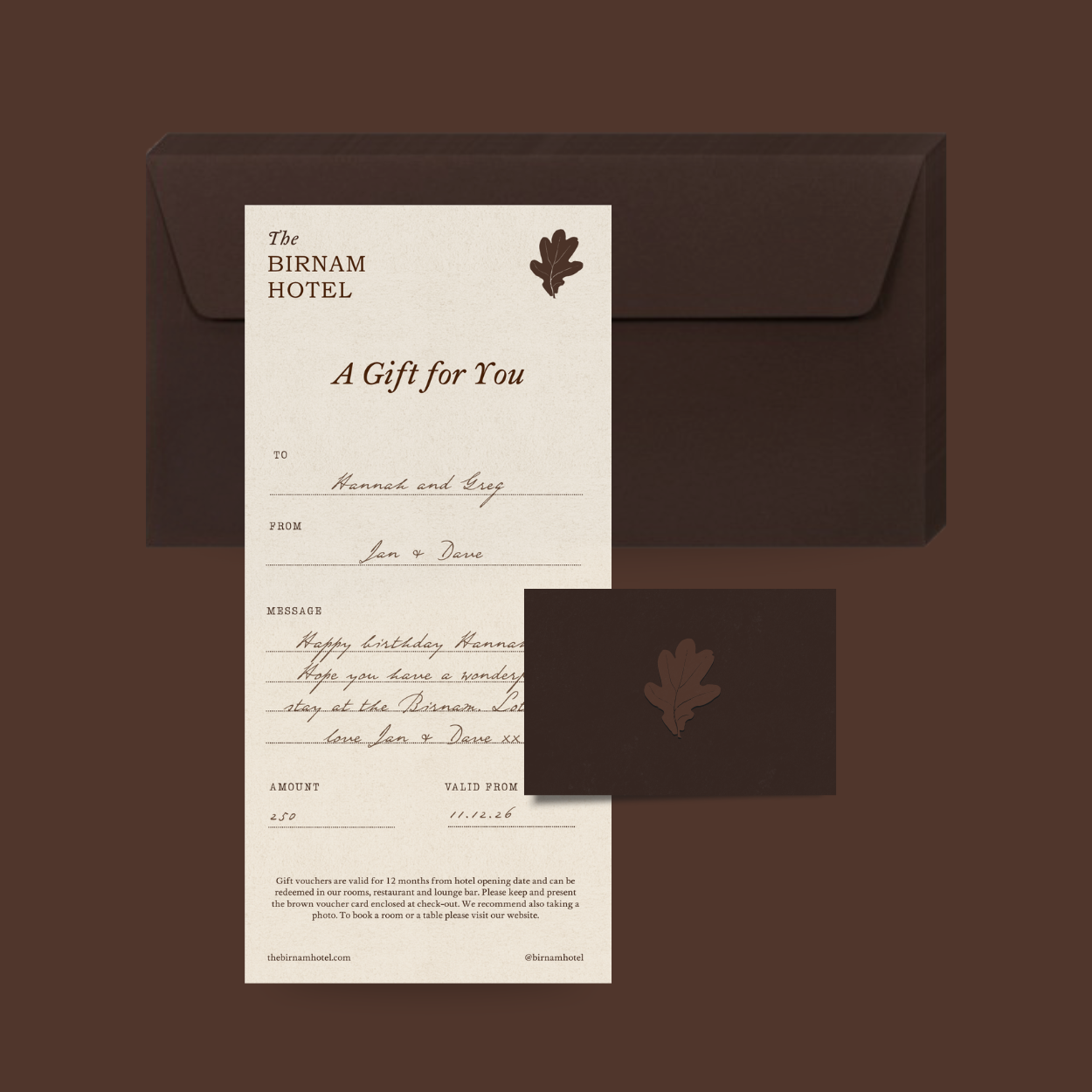 Gift voucher from The Birnam Hotel with a brown envelope and a matching brown note card, featuring a leaf in the top right corner and handwritten message, on a brown background.