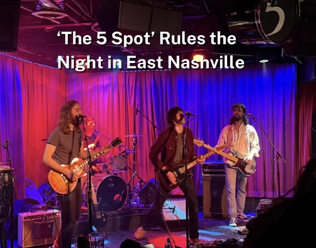 A band performing on stage with blue and red curtains, three musicians are visible: one singing and playing guitar, one playing bass, and a drummer in the background. The scene is lit with colorful stage lights at the 5 Spot in Nashville, TN. 