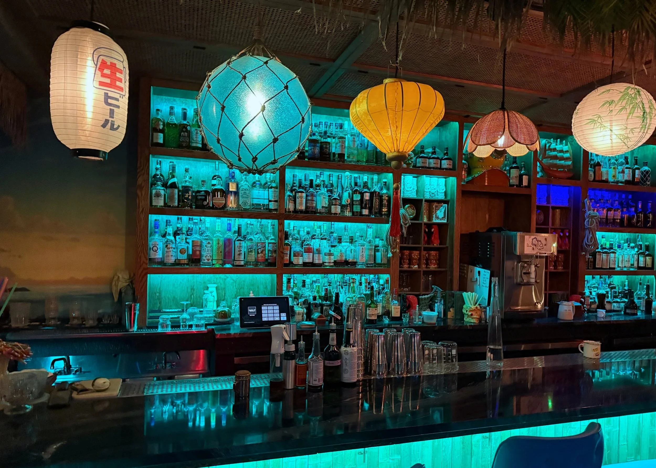 A view of the light fixtures and bar at Easy Sailor tiki. The bar is loaded with many interesting rum and other liqueur varieties.