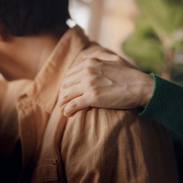 Person reaching out and comforting another by putting their hand on their shoulder