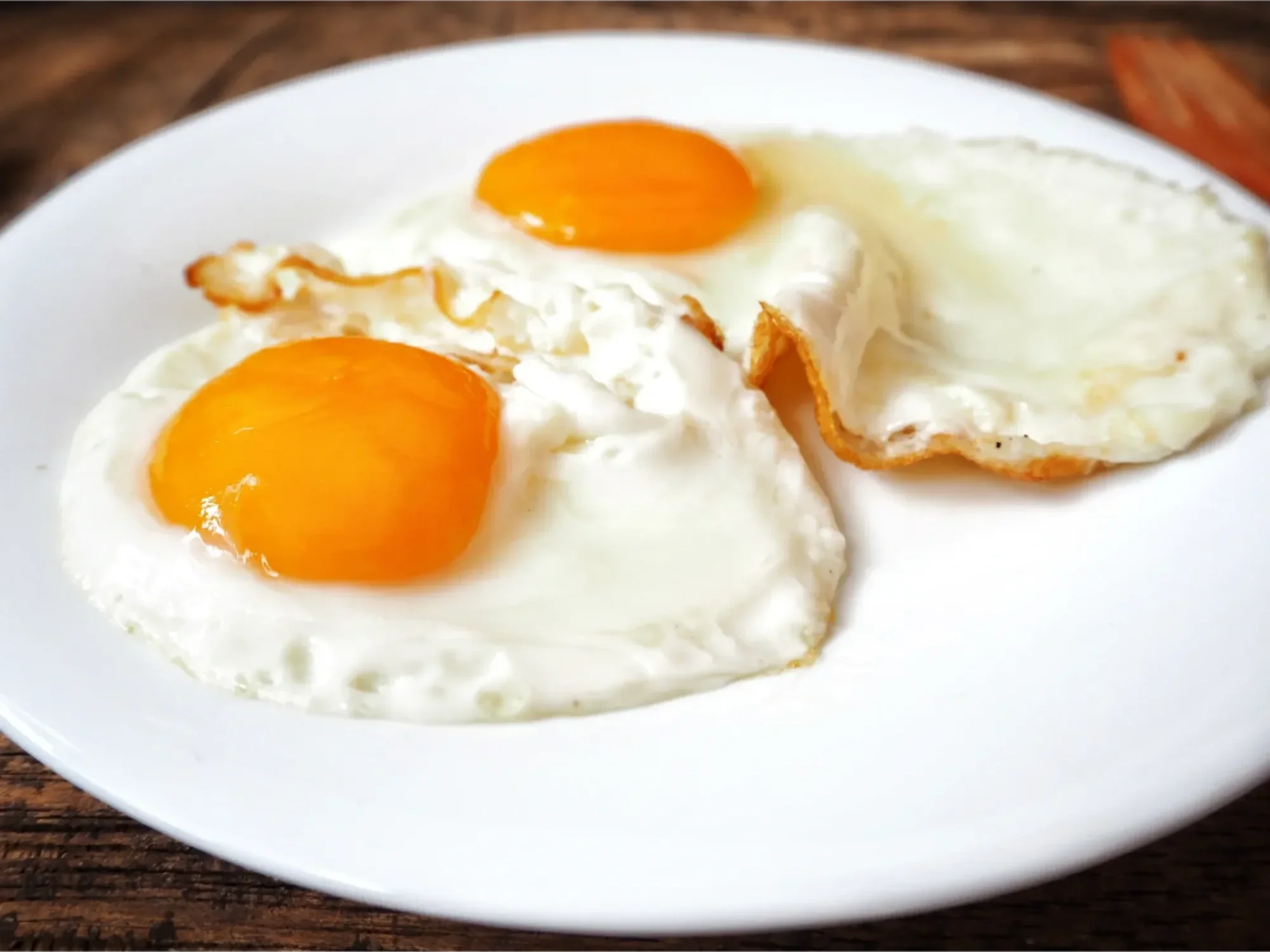 fried-eggs-white-plate-table.webp