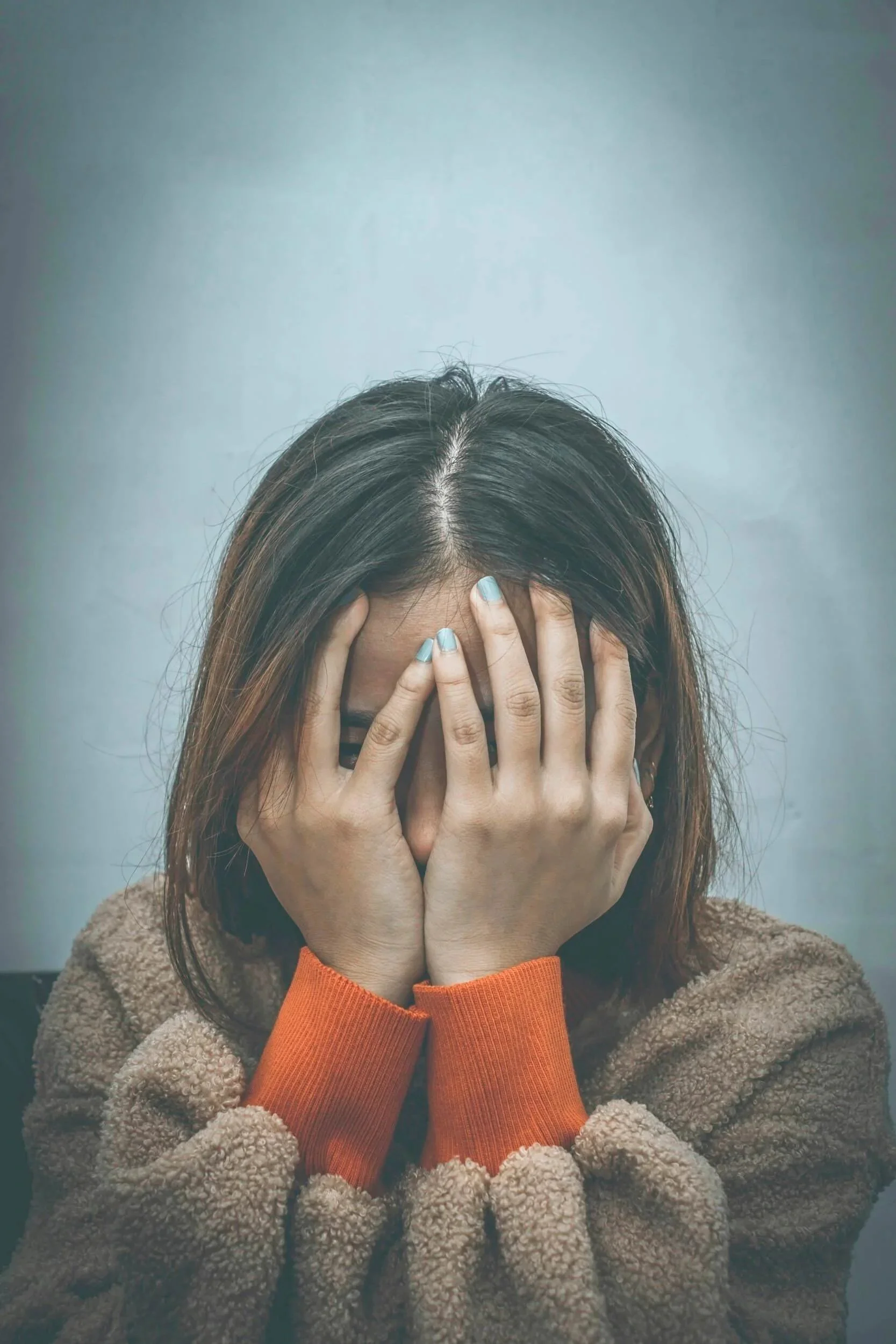 A high achieving teen covering their face with their hands.