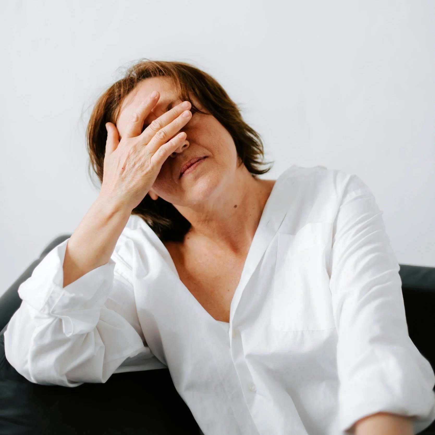 A stressed adult holding their hand over their face.