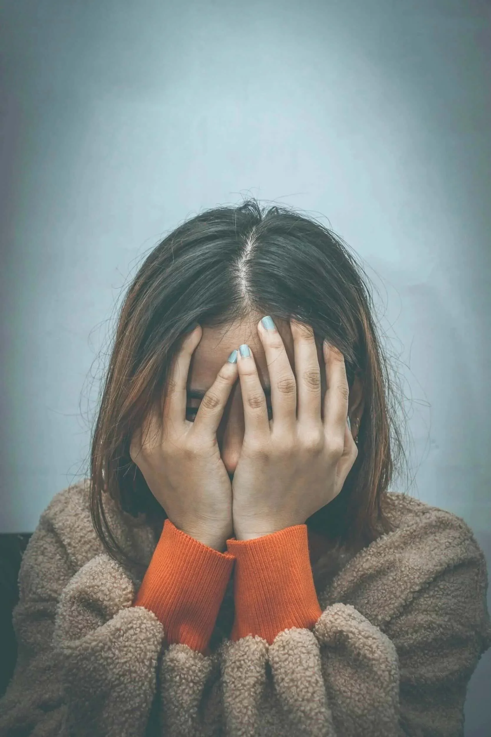 A high achieving teen covering their face with their hands.
