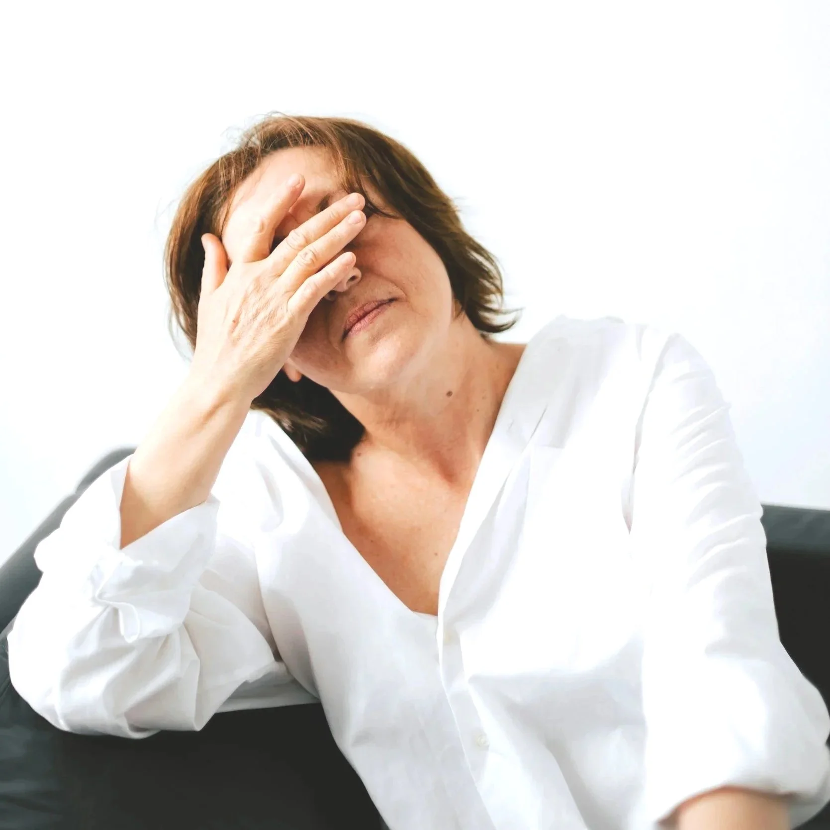 A stressed adult holding their hand over their face. 