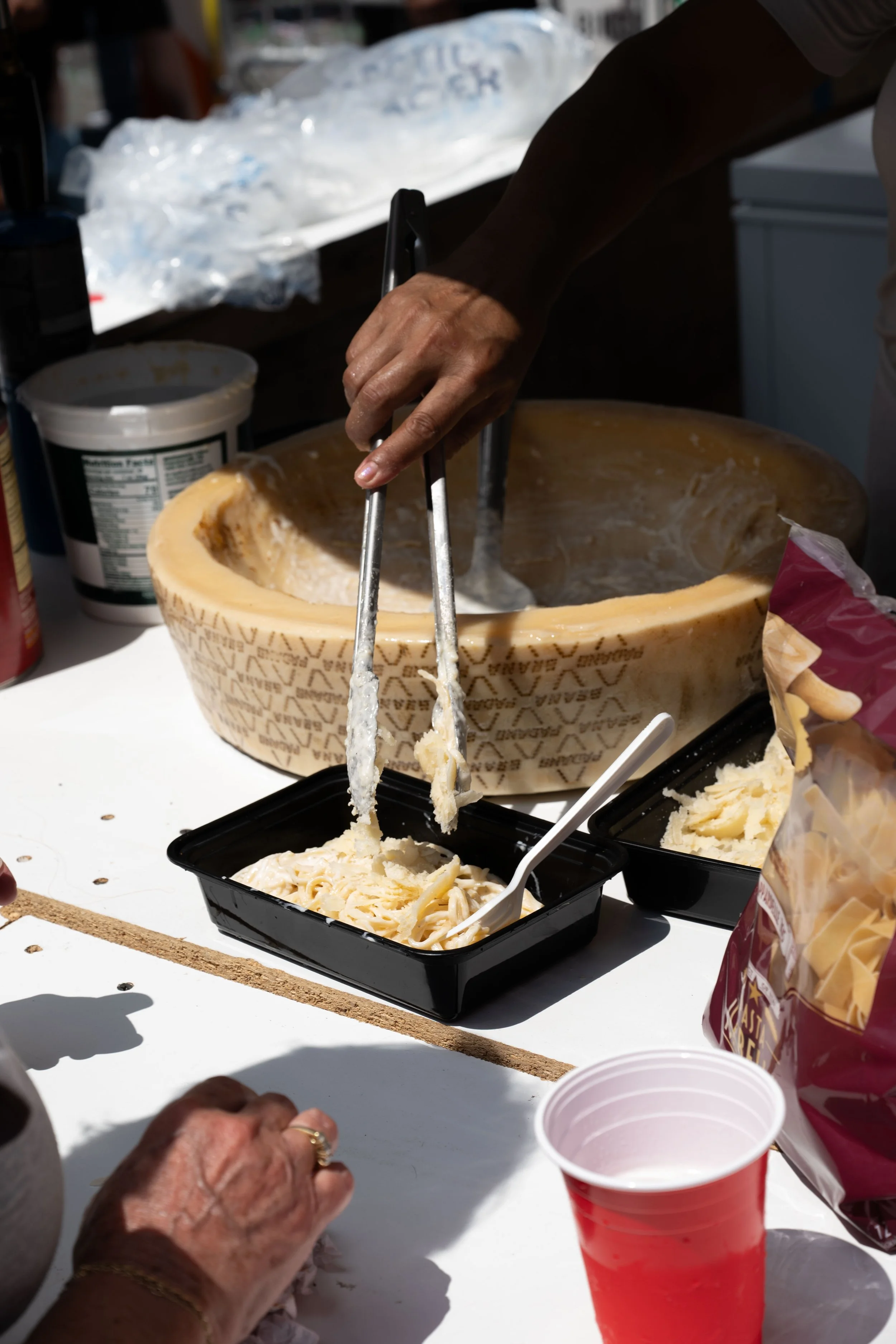 A woman orders pasta freshly spun from the cheese wheel at a food stall at the Our Lady of Mount Carmel Feast, an annual Italian-American multi-day celebration, on July 13, 2025 in Williamsburg, Brooklyn.